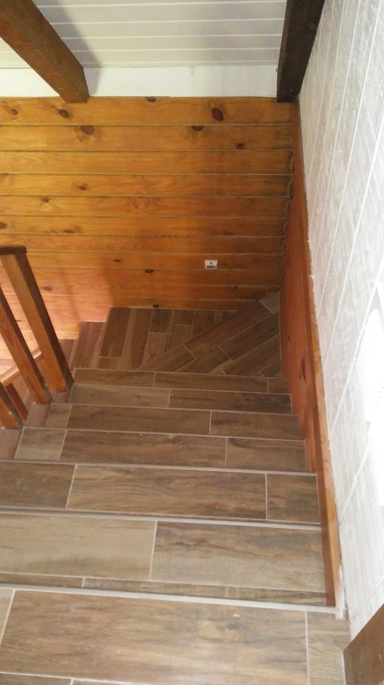 Cette photo montre un escalier carrelé nature en L de taille moyenne avec des contremarches carrelées et un garde-corps en bois.