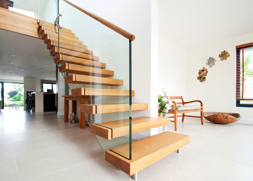 Exempel på en mellanstor modern rak trappa i trä, med sättsteg i trä och räcke i glas