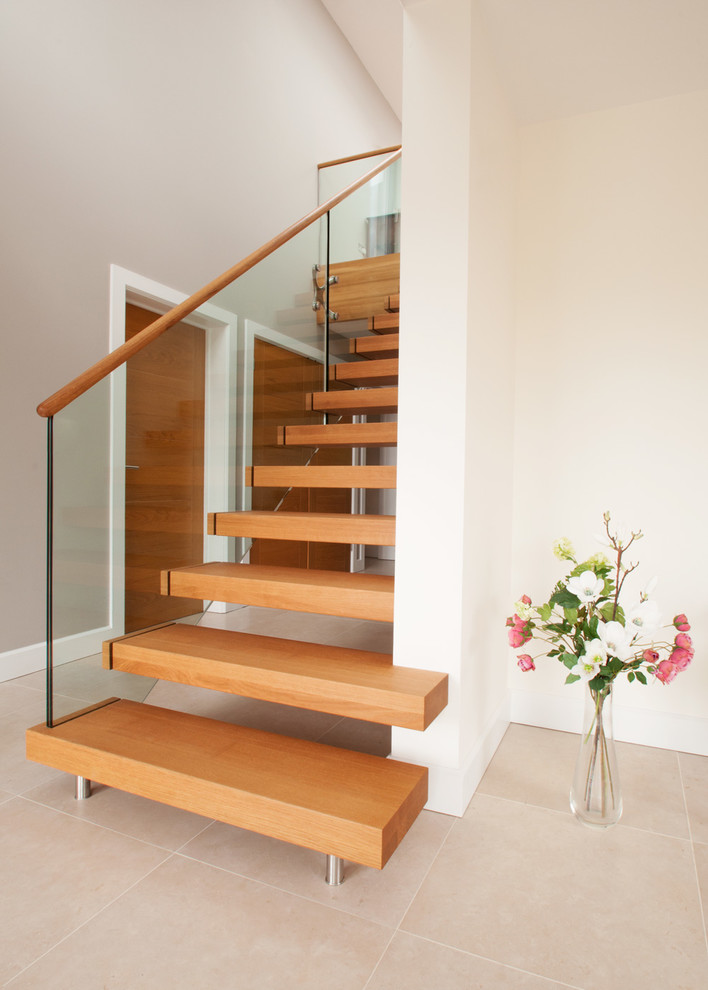Ejemplo de escalera recta minimalista de tamaño medio con escalones de madera, contrahuellas de madera y barandilla de vidrio