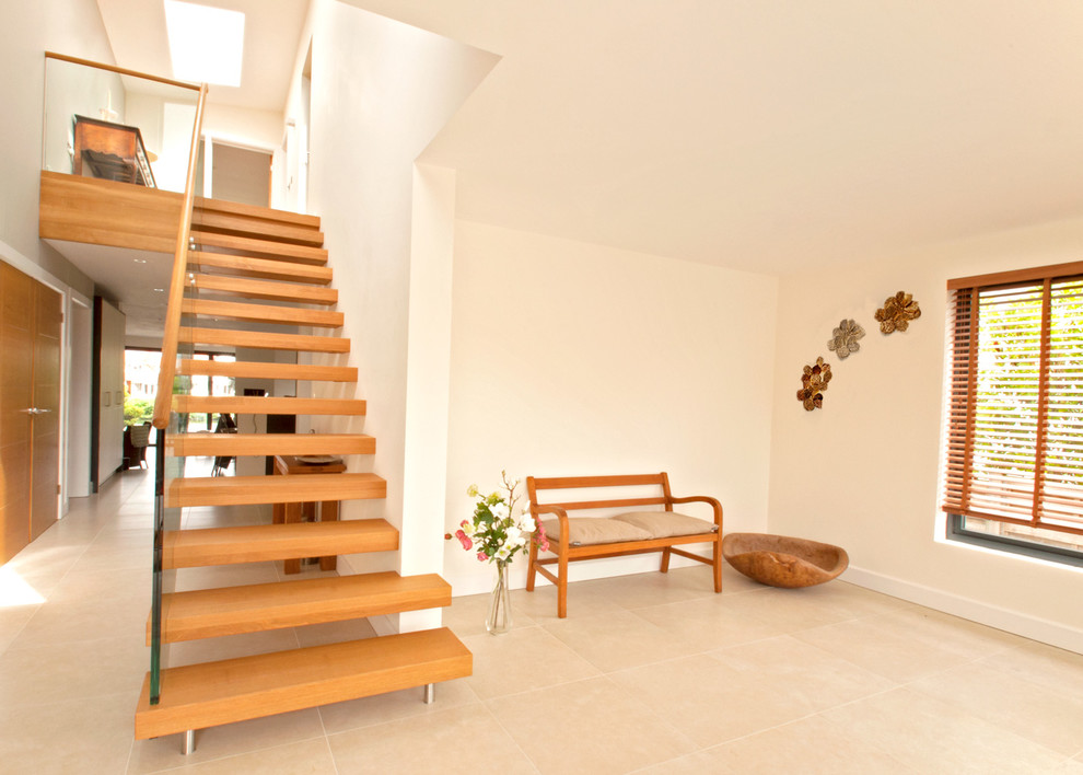 Foto de escalera recta moderna de tamaño medio con escalones de madera, contrahuellas de madera y barandilla de vidrio