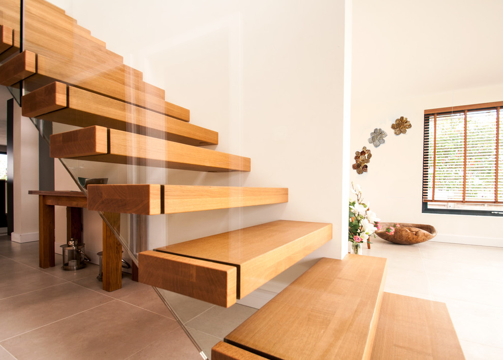 Diseño de escalera recta minimalista de tamaño medio con escalones de madera, contrahuellas de madera y barandilla de vidrio