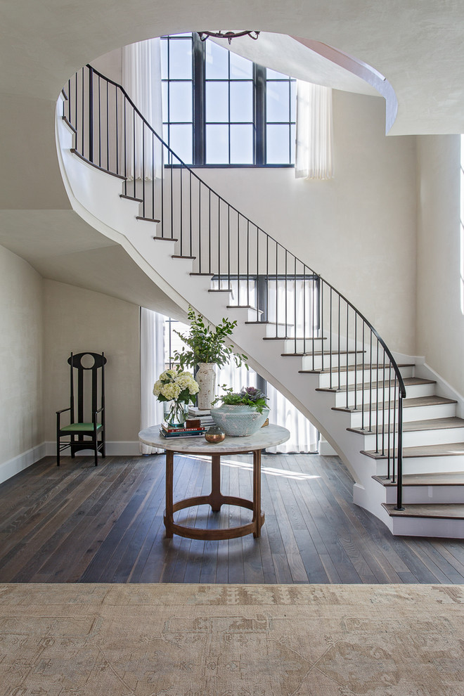 Идея дизайна: изогнутая лестница в морском стиле с деревянными ступенями, металлическими перилами и крашенными деревянными подступенками