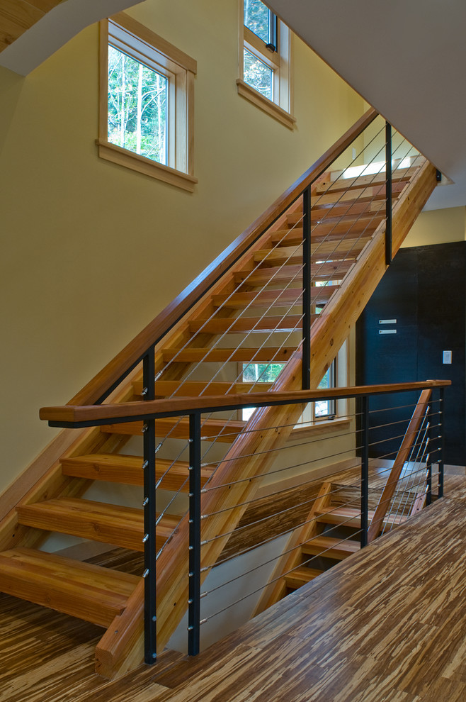 Cette image montre un grand escalier sans contremarche droit design avec des marches en bois et un garde-corps en câble.