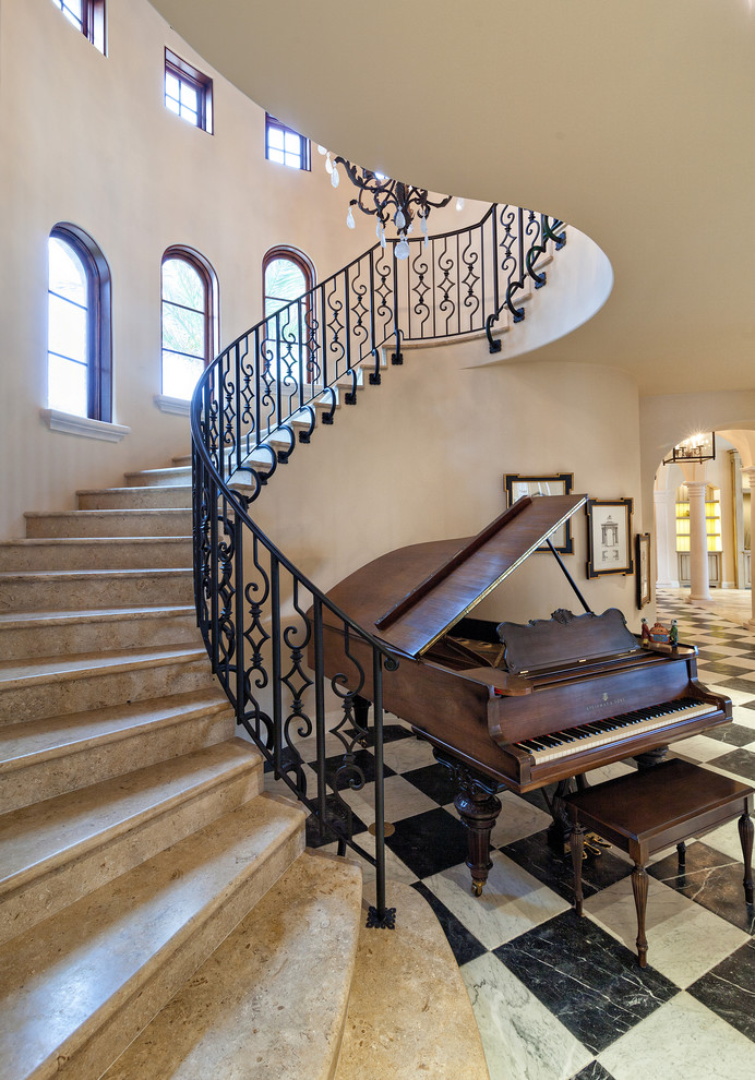 Пример оригинального дизайна: изогнутая лестница в средиземноморском стиле с мраморными ступенями, подступенками из мрамора и металлическими перилами