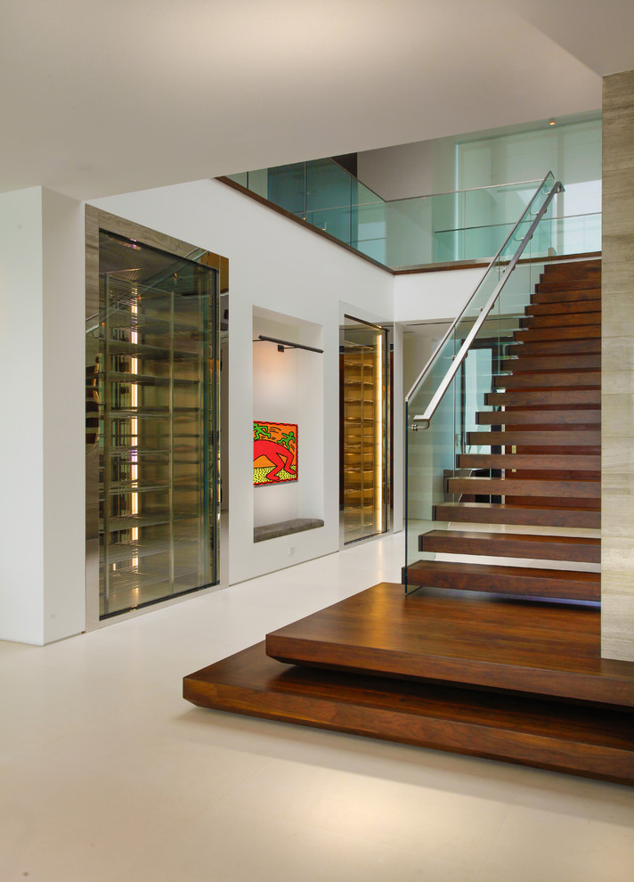 На фото: лестница на больцах в стиле модернизм с деревянными ступенями и стеклянными перилами без подступенок
