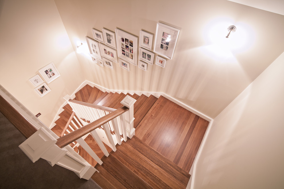 Imagen de escalera tradicional con escalones de madera, contrahuellas de madera pintada y barandilla de madera