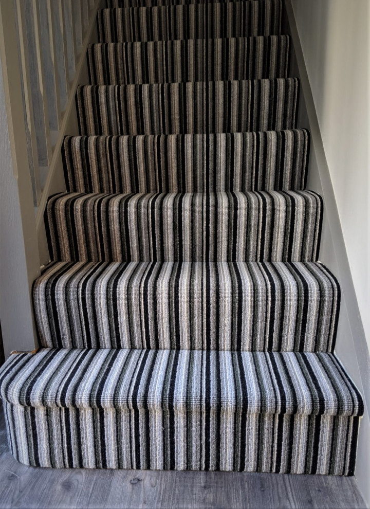 Imagen de escalera curva contemporánea grande con escalones enmoquetados, contrahuellas de madera y barandilla de madera