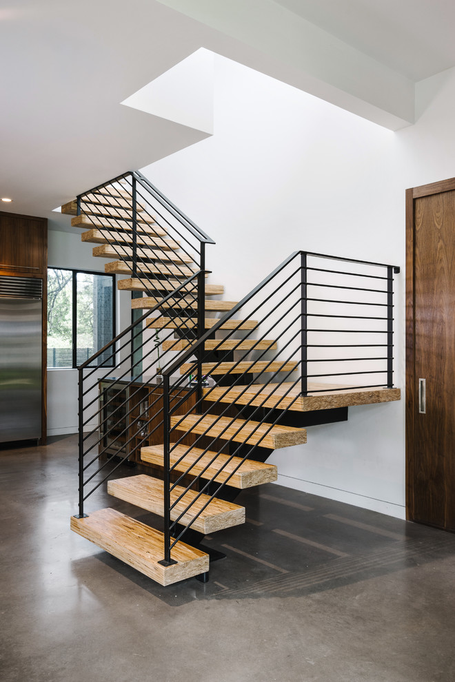 Large minimalist wooden l-shaped open and metal railing staircase photo in Austin