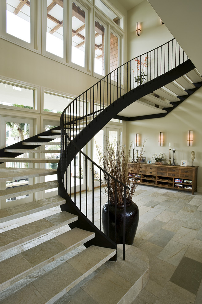 Imagen de escalera suspendida moderna grande sin contrahuella con escalones de piedra caliza y barandilla de metal
