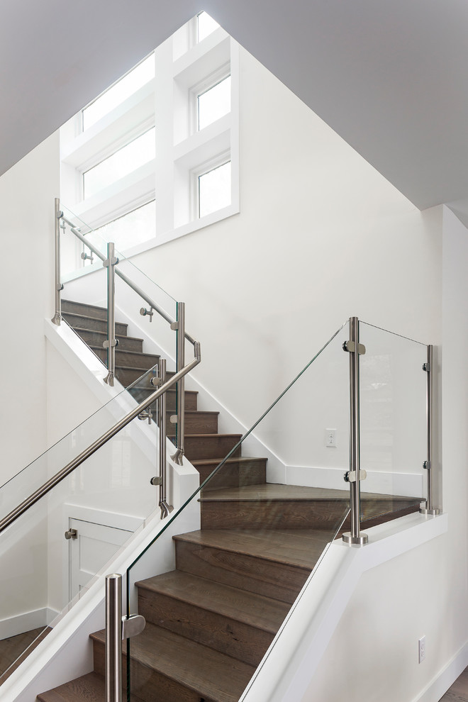 Ejemplo de escalera en L minimalista con escalones de madera, contrahuellas de madera y barandilla de vidrio