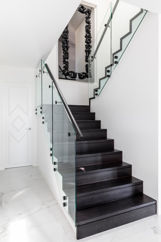Large trendy wooden u-shaped glass railing staircase photo in Sydney with wooden risers