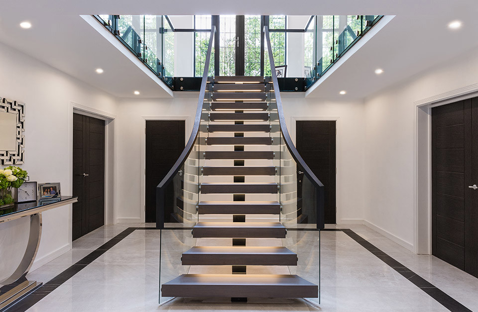 Imagen de escalera curva actual grande sin contrahuella con escalones de madera y barandilla de vidrio