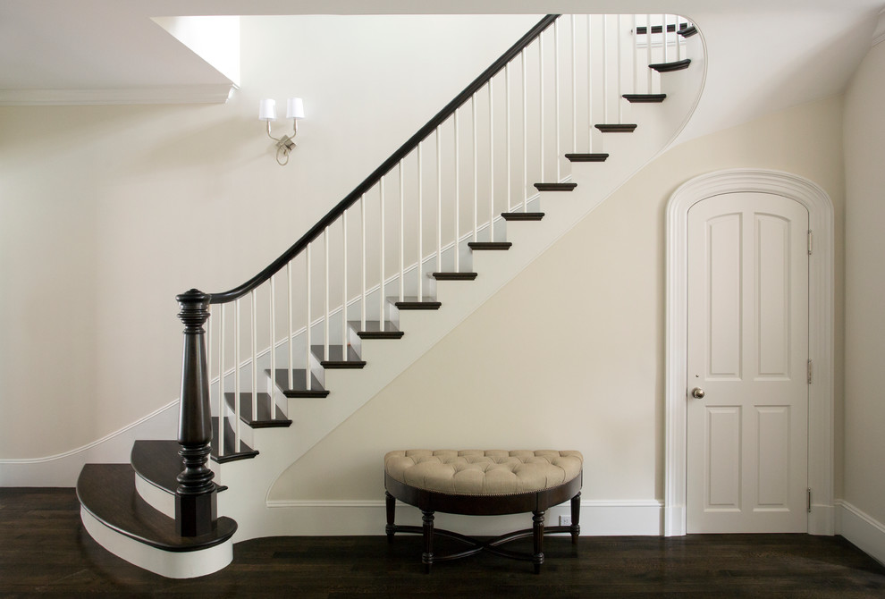 Foto de escalera curva clásica grande con escalones de madera y contrahuellas de madera pintada