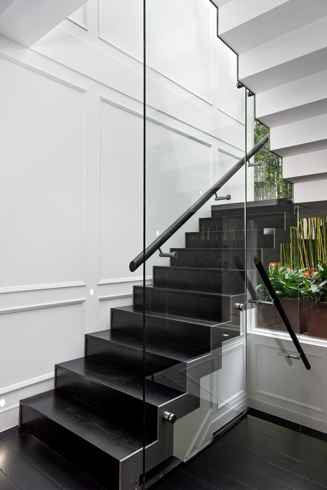 Свежая идея для дизайна: п-образная лестница в современном стиле с стеклянными перилами и панелями на части стены - отличное фото интерьера