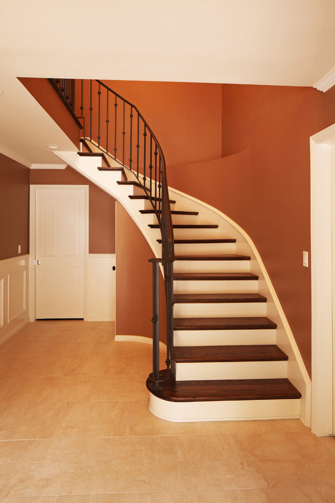 Ejemplo de escalera curva clásica de tamaño medio con escalones de madera y contrahuellas de madera