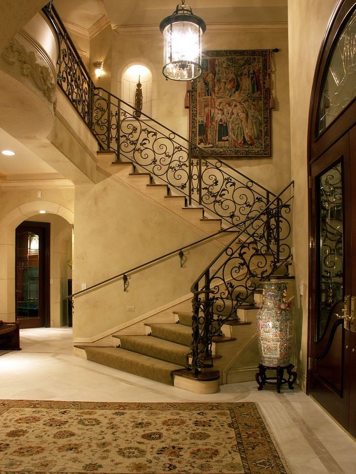 На фото: огромная изогнутая лестница в классическом стиле с ступенями с ковровым покрытием и ковровыми подступенками