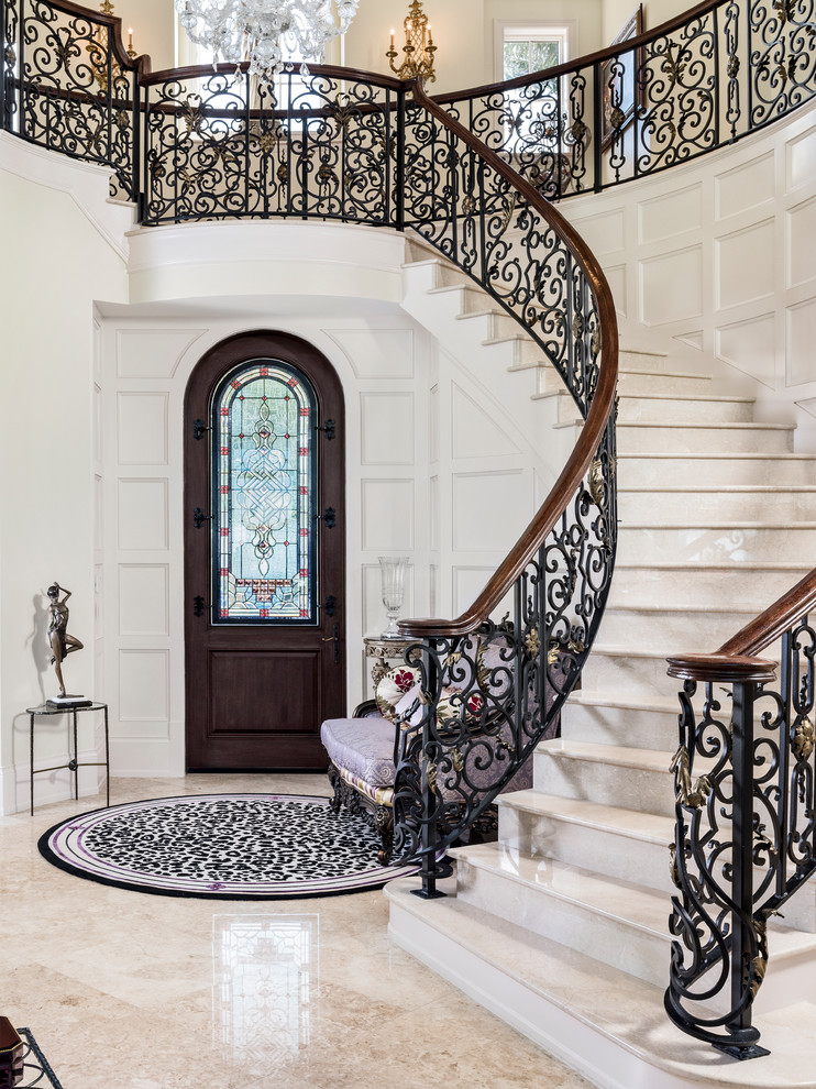 Стильный дизайн: изогнутая лестница в средиземноморском стиле с мраморными ступенями, подступенками из мрамора и перилами из смешанных материалов - последний тренд
