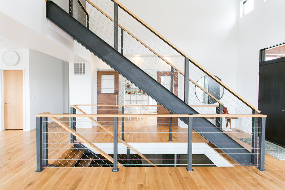 Inspiration for a medium sized modern wood straight wire cable railing staircase in Cleveland with open risers.