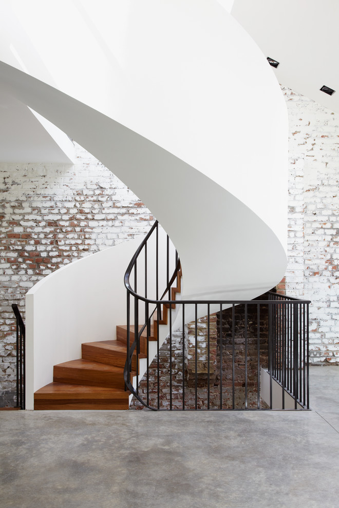 This is an example of a contemporary wood curved staircase in London with wood risers.