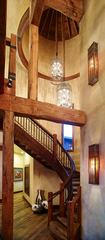 Example of a huge mountain style wooden curved open staircase design in Denver