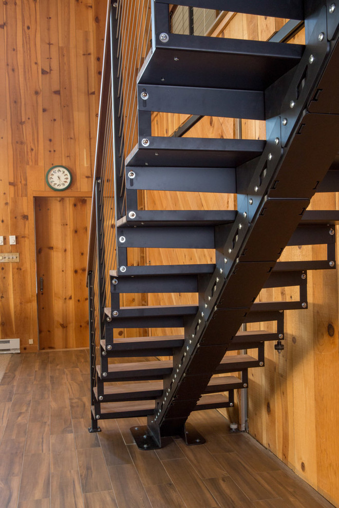 Cette image montre un escalier flottant chalet de taille moyenne avec des marches en bois, des contremarches en métal et un garde-corps en bois.