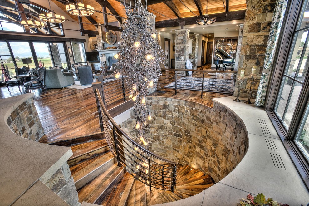 Huge mountain style wooden spiral staircase photo in Denver with wooden risers