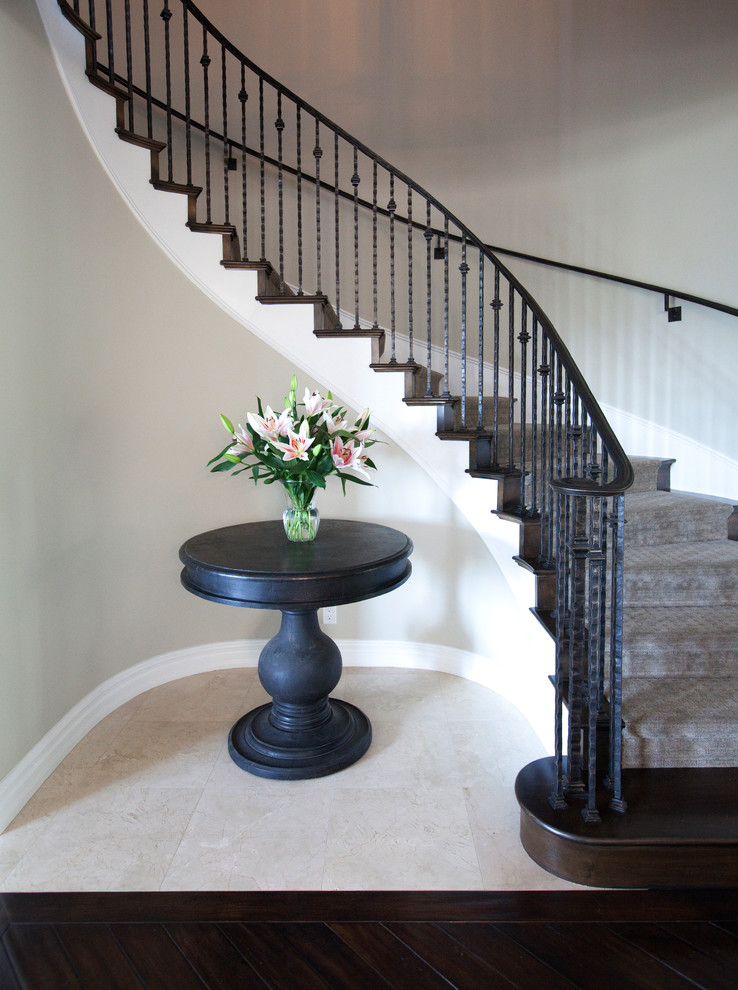 Inspiration for a large classic carpeted curved metal railing staircase in Orange County with carpeted risers.