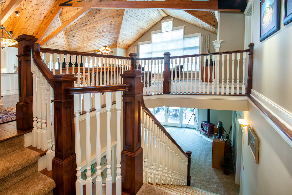 На фото: большая лестница в стиле рустика с деревянными ступенями и крашенными деревянными подступенками