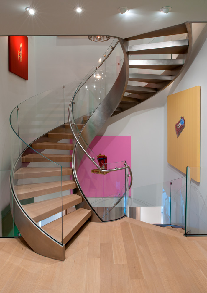 Пример оригинального дизайна: огромная винтовая лестница в стиле модернизм с деревянными ступенями и стеклянными перилами без подступенок