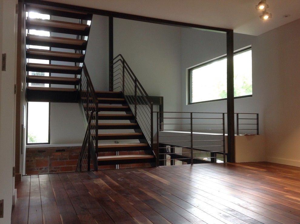 Imagen de escalera en U urbana grande sin contrahuella con escalones de madera y barandilla de metal