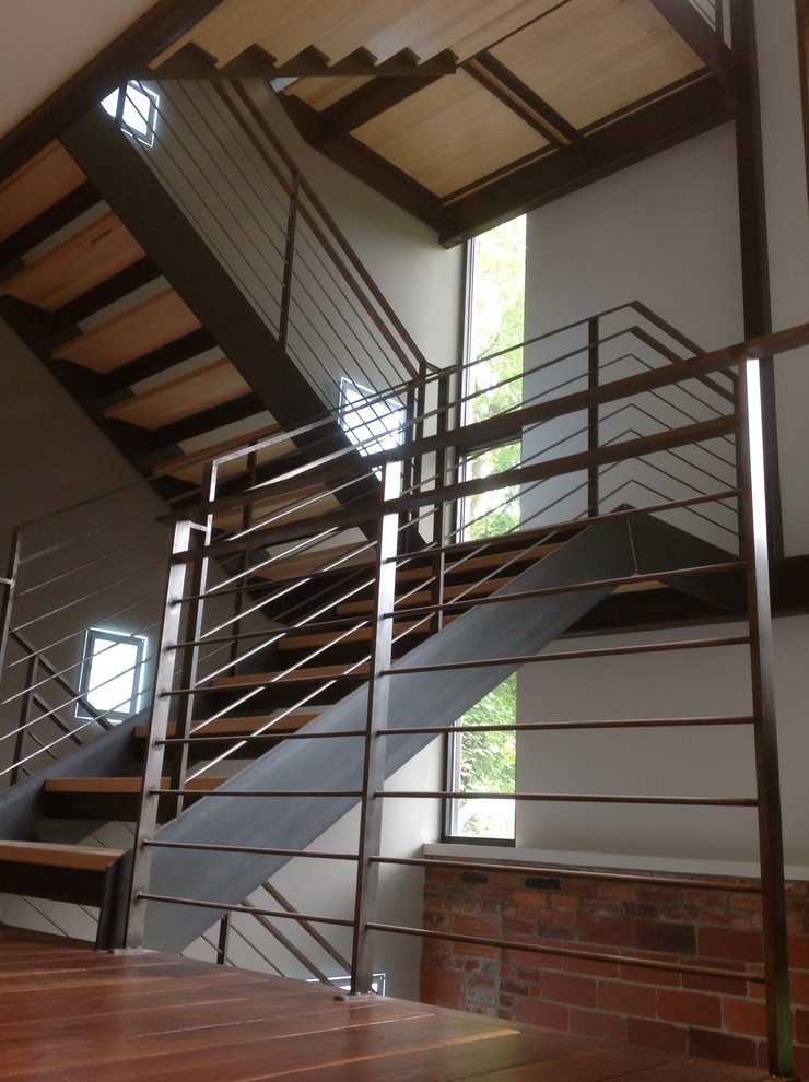 Пример оригинального дизайна: большая п-образная лестница в стиле лофт с деревянными ступенями и металлическими перилами без подступенок