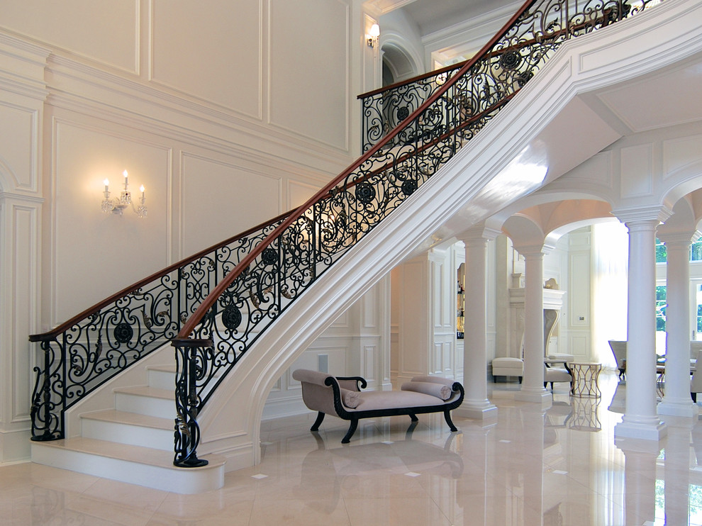 Bild på en stor vintage svängd trappa i marmor, med sättsteg i marmor och räcke i metall