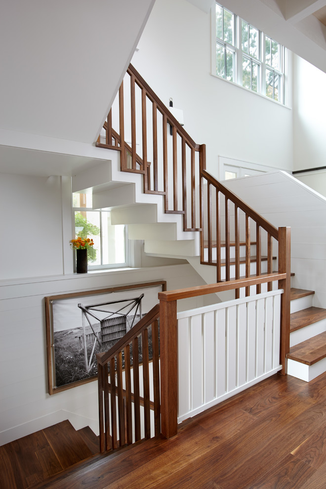 This is an example of an expansive beach style wood l-shaped staircase in Boston with painted wood risers.