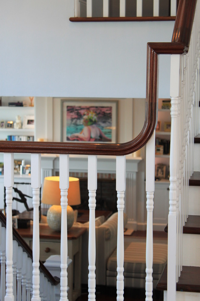 На фото: большая п-образная лестница в классическом стиле с деревянными ступенями и крашенными деревянными подступенками с