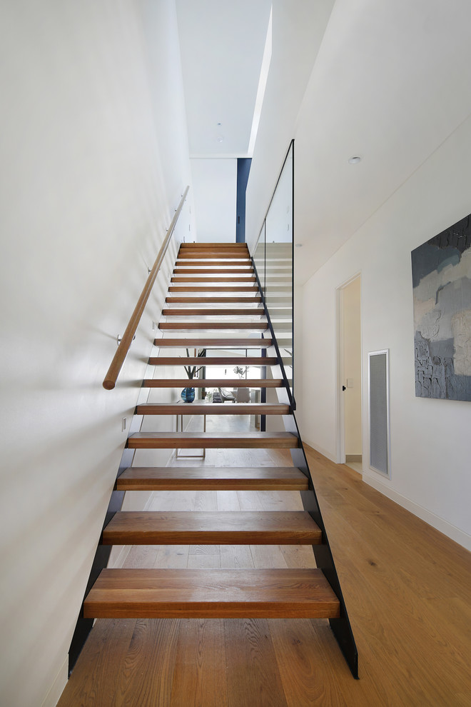 Idée de décoration pour un grand escalier droit design avec des marches en bois et un garde-corps en matériaux mixtes.