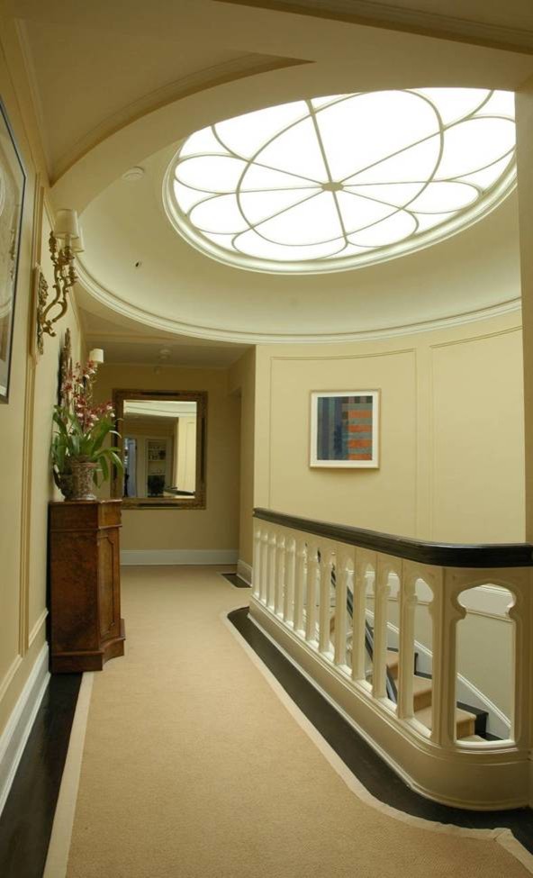 Пример оригинального дизайна: лестница в классическом стиле с ступенями с ковровым покрытием, ковровыми подступенками, деревянными перилами и панелями на части стены