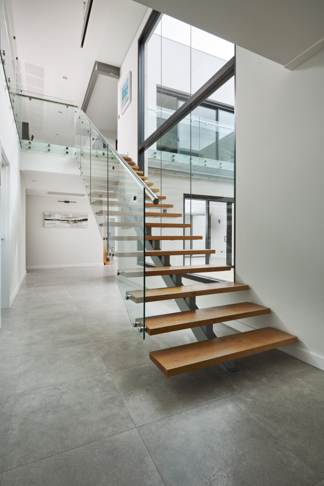 Источник вдохновения для домашнего уюта: лестница на больцах, среднего размера в стиле модернизм с деревянными ступенями и стеклянными перилами без подступенок