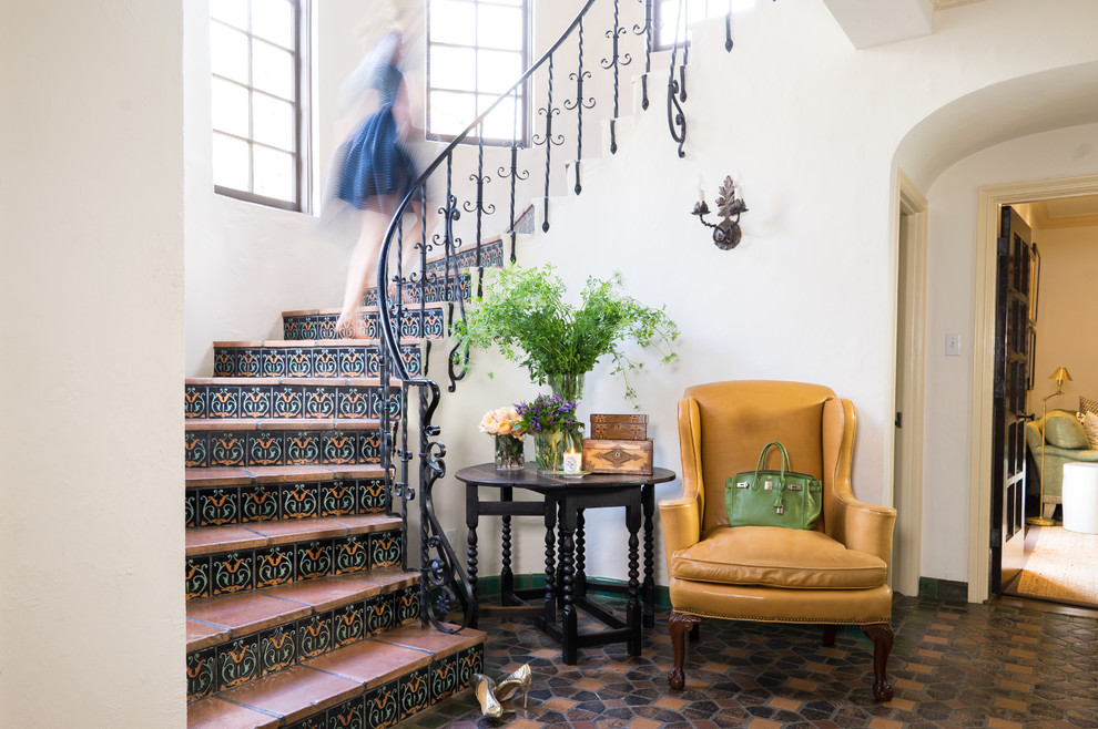 Пример оригинального дизайна: изогнутая лестница в средиземноморском стиле с подступенками из плитки, ступенями из терракотовой плитки и металлическими перилами