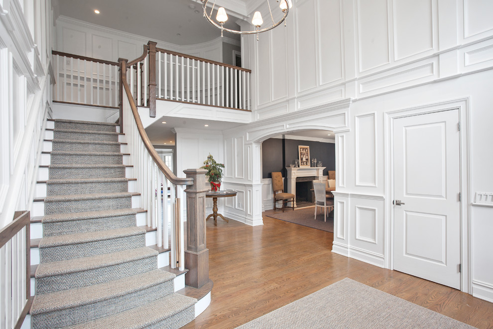 Large elegant wooden l-shaped wood railing staircase photo in New York with painted risers