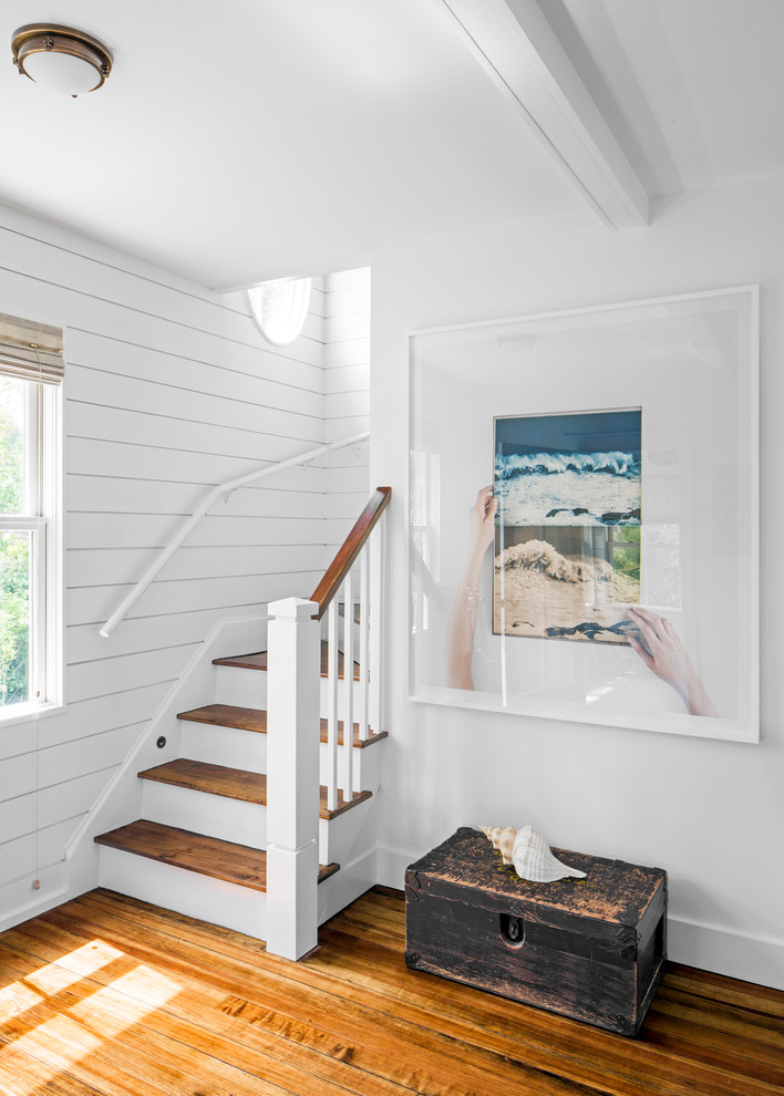 Cette image montre un petit escalier peint courbe marin avec des marches en bois peint, un garde-corps en bois et éclairage.