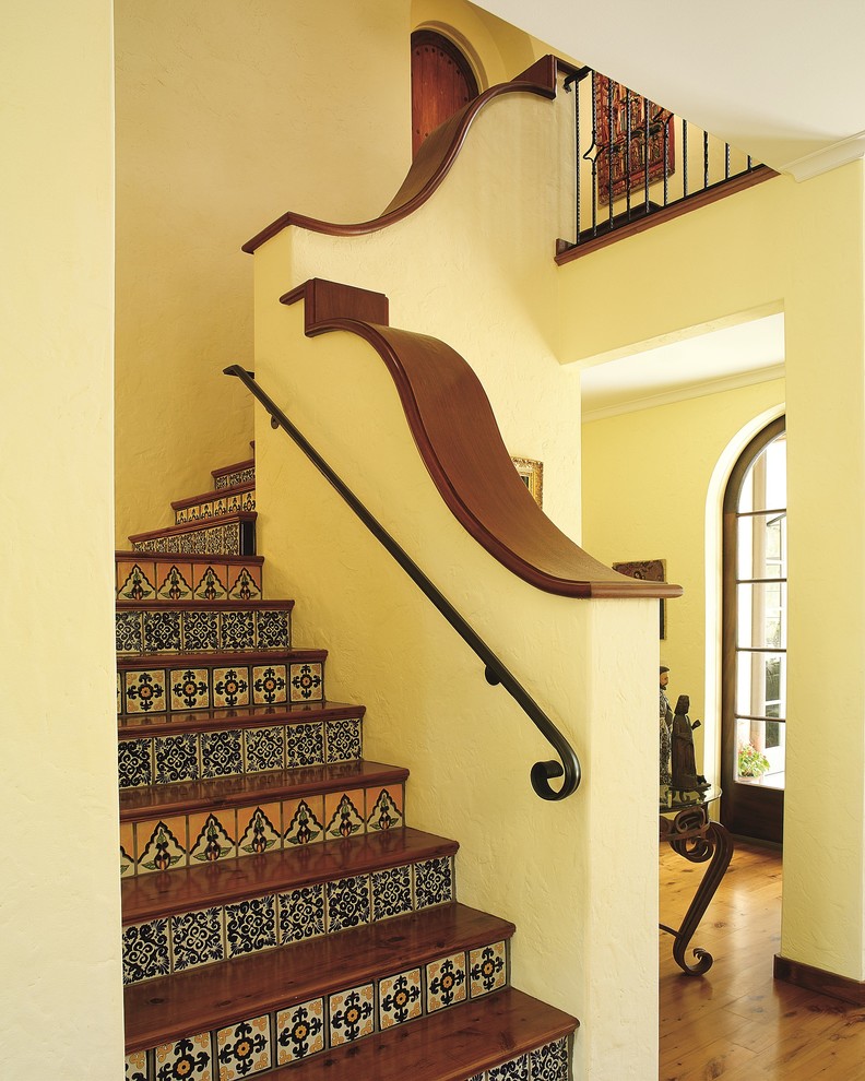 Imagen de escalera en L mediterránea con escalones de madera y contrahuellas con baldosas y/o azulejos
