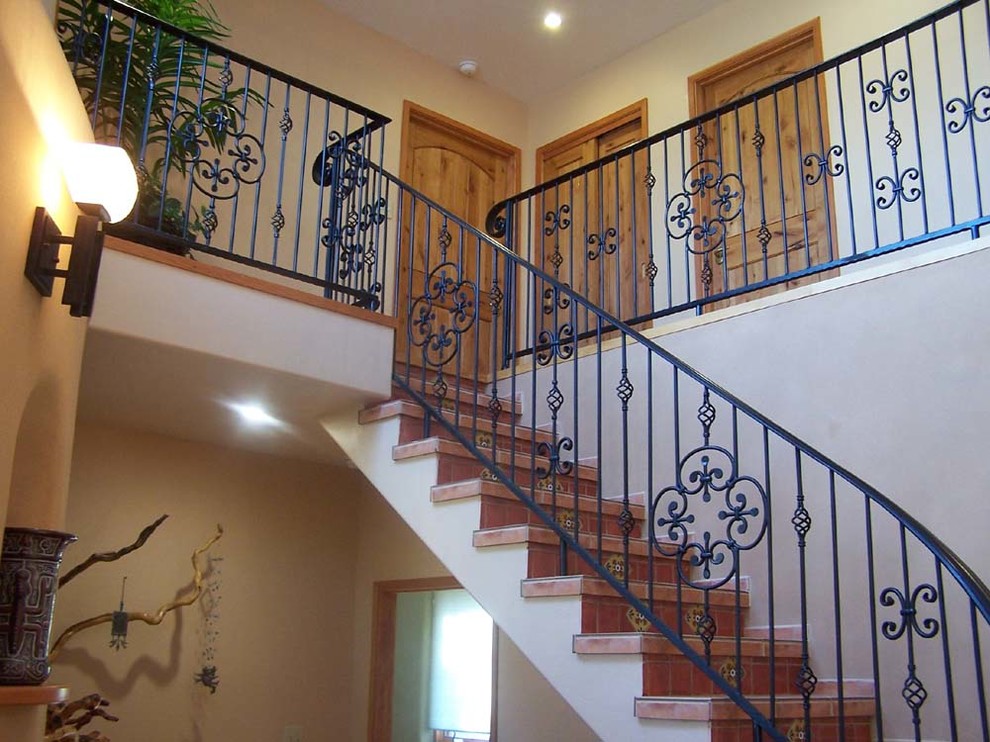 На фото: большая изогнутая деревянная лестница в стиле фьюжн с ступенями из плитки с