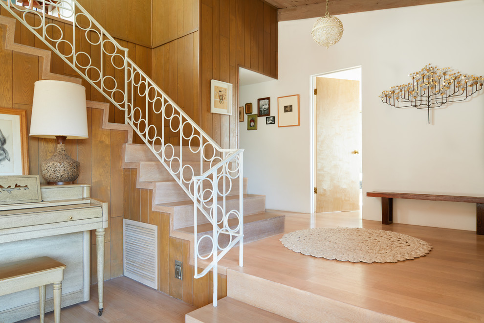 Idée de décoration pour un escalier vintage en L avec des marches en bois, des contremarches en bois, un garde-corps en métal, palier et éclairage.
