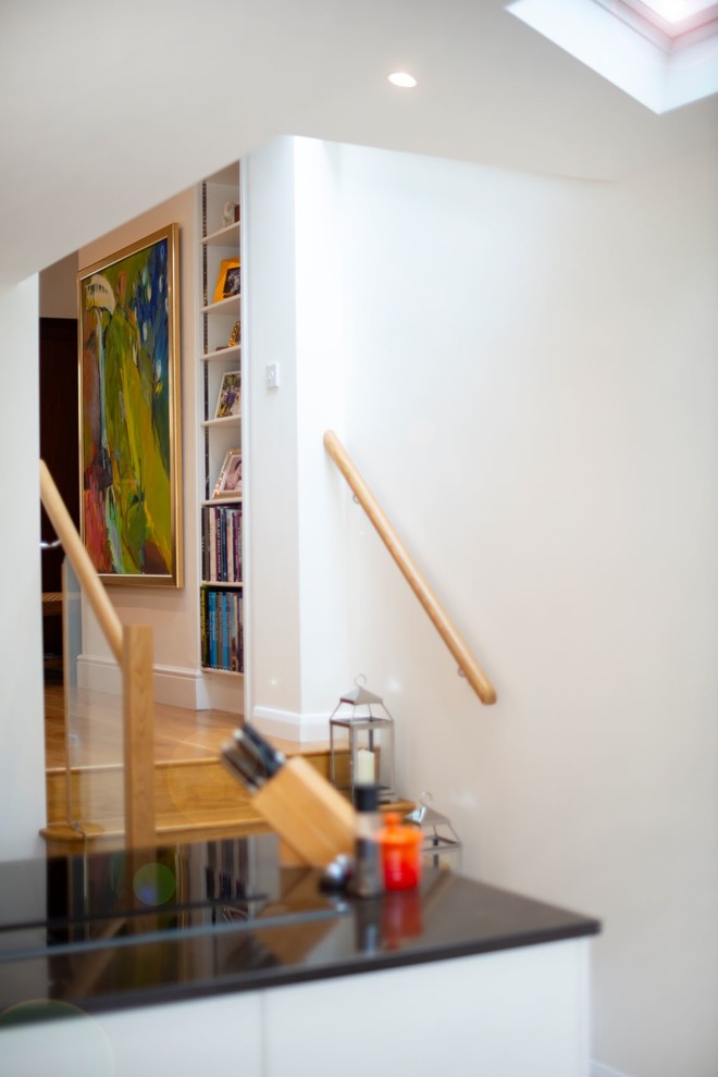 Cette photo montre un escalier droit tendance de taille moyenne avec des marches en bois, des contremarches en travertin et un garde-corps en verre.