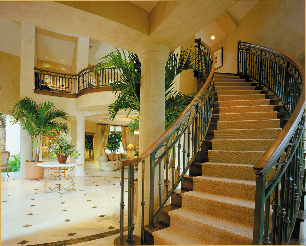 На фото: большая изогнутая деревянная лестница в средиземноморском стиле с деревянными ступенями с