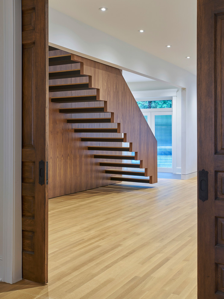 Inspiration pour un escalier flottant minimaliste avec des marches en bois, des contremarches en métal et un garde-corps en bois.