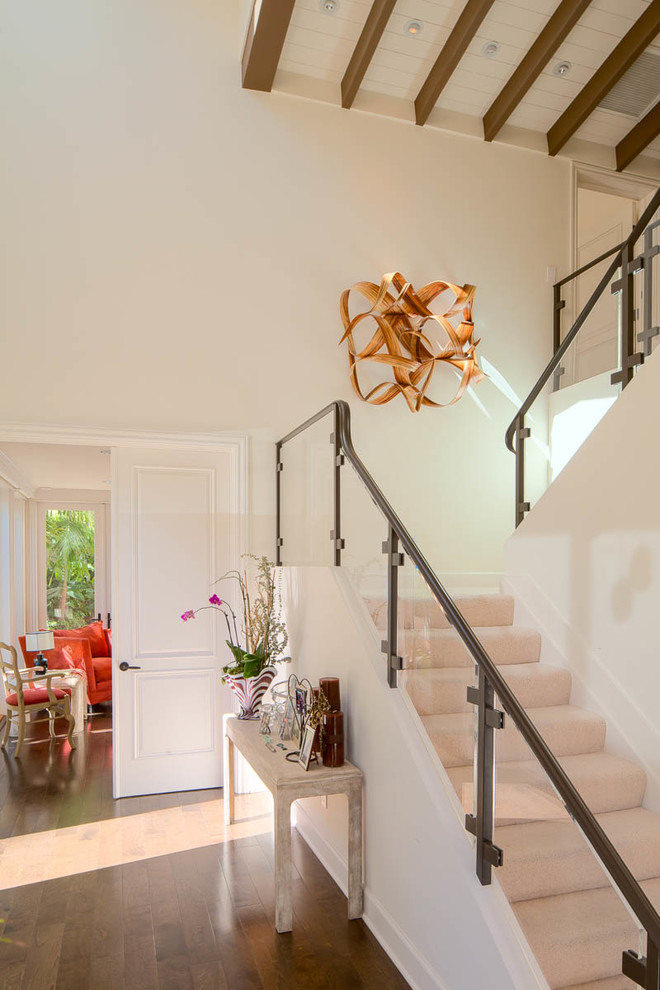 Cette image montre un escalier design en U de taille moyenne avec des marches en moquette, des contremarches en moquette et un garde-corps en verre.