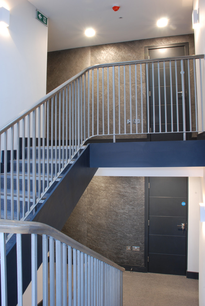 Imagen de escalera en U actual de tamaño medio con escalones enmoquetados, contrahuellas enmoquetadas y barandilla de varios materiales