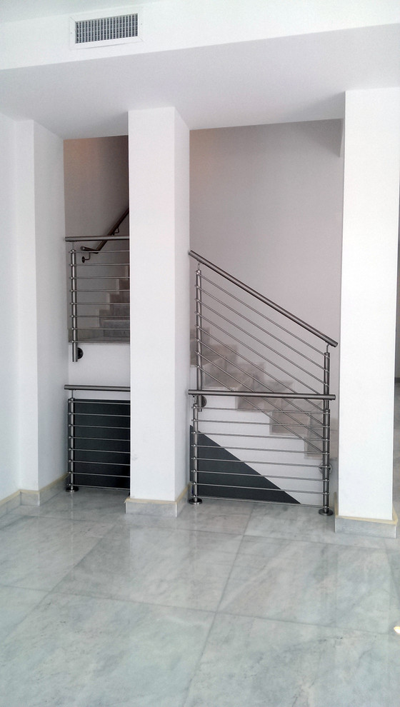 Diseño de escalera en L minimalista de tamaño medio con escalones con baldosas, contrahuellas con baldosas y/o azulejos y barandilla de metal