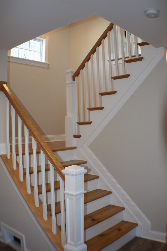 Imagen de escalera en U pequeña con escalones de madera, contrahuellas de madera y barandilla de madera